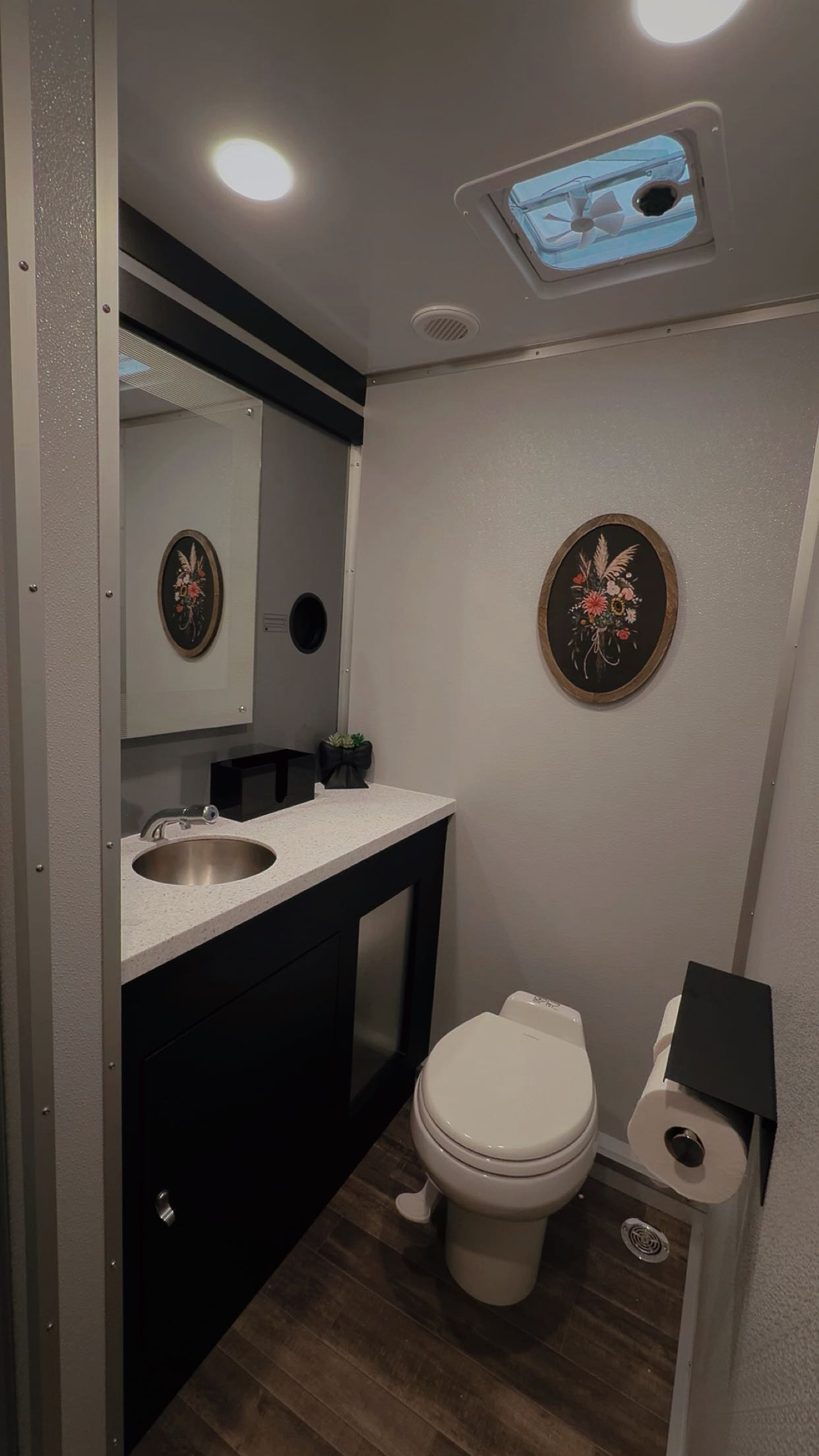 Clean luxury restroom trailer suite with vanity, mirror and flushing toilet