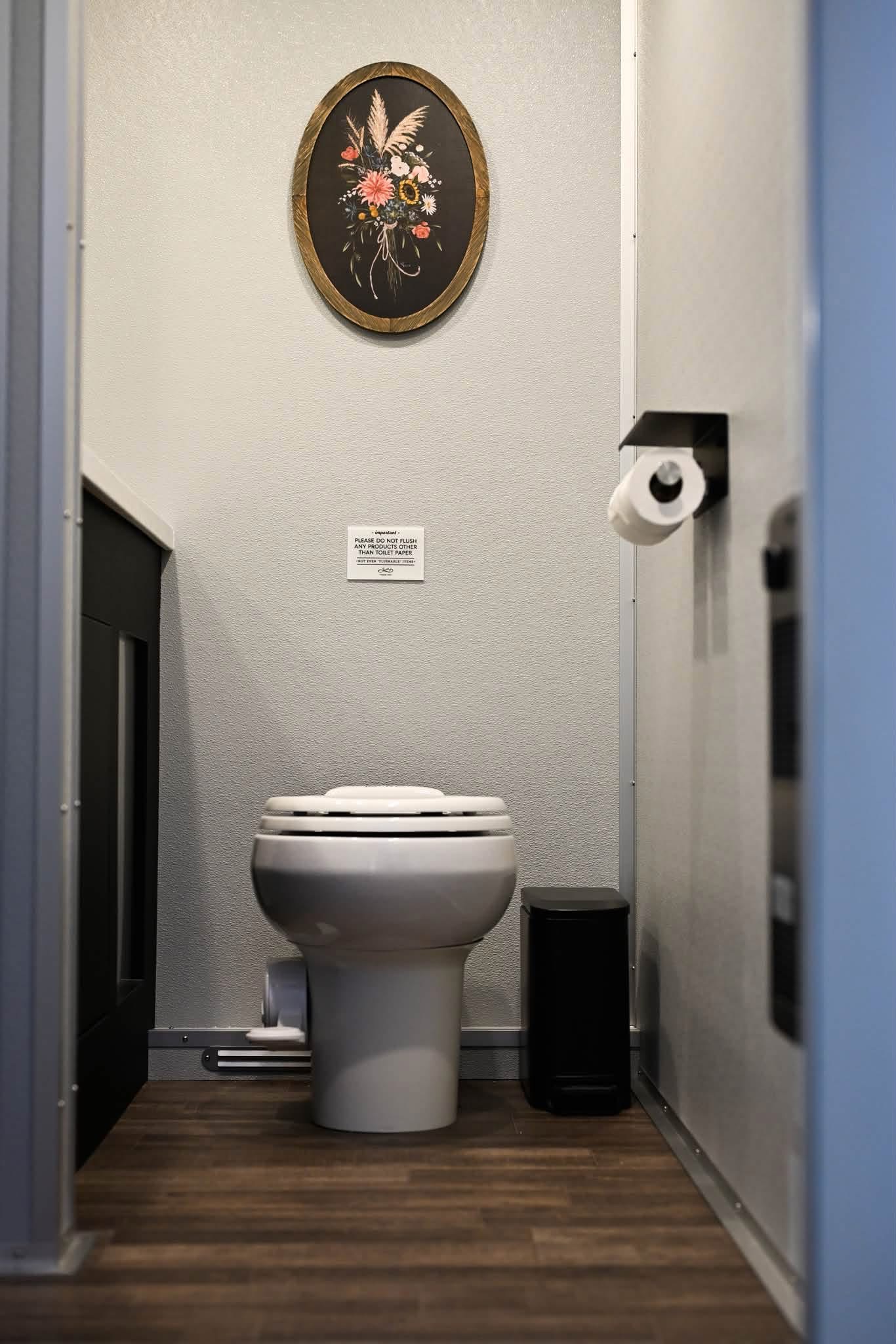 Private restroom suite with flushing toilet and floral decor
