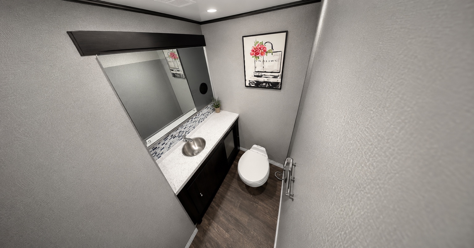 Clean luxury restroom trailer interior with vanity and flushing toilet